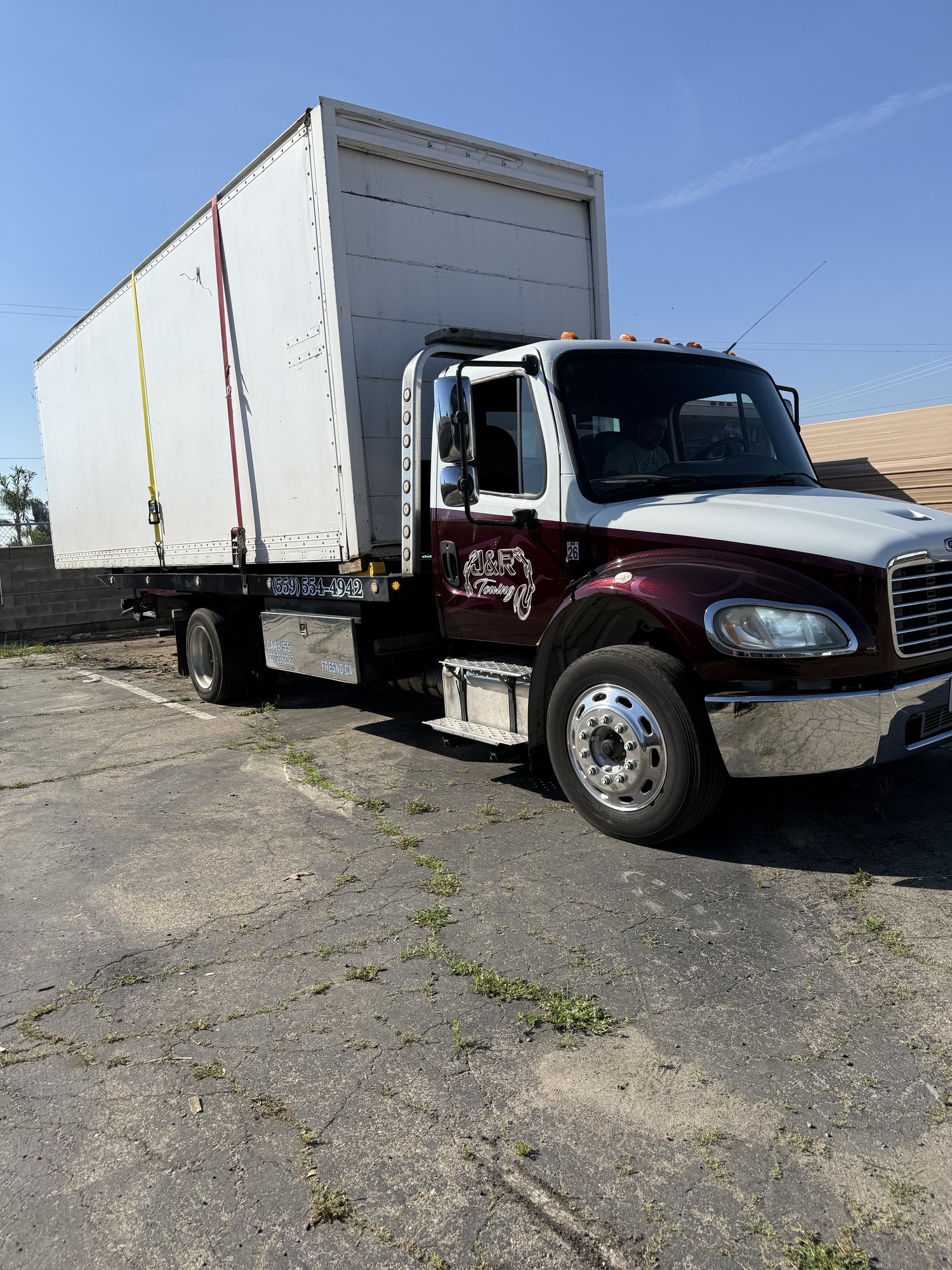 J&R Towing truck moving a large container