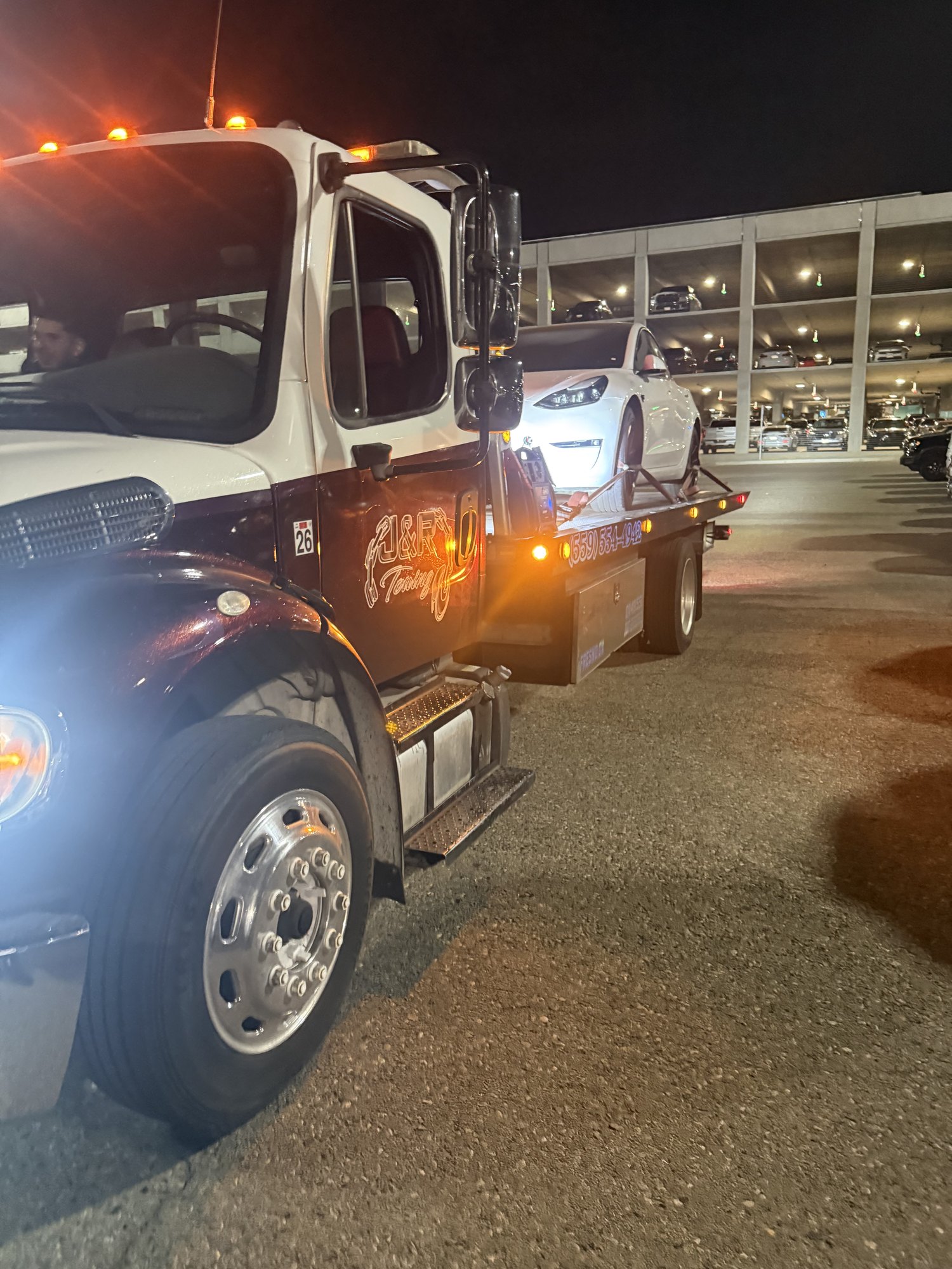J&R Towing flatbed transporting a vehicle at night